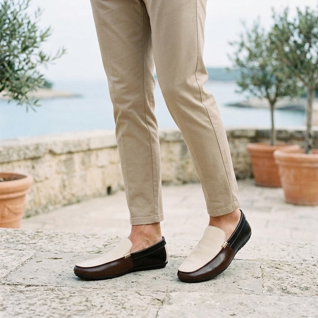 Stresa Two-Tone Loafers — Cream & Brown, worn on a coastal stone terrace