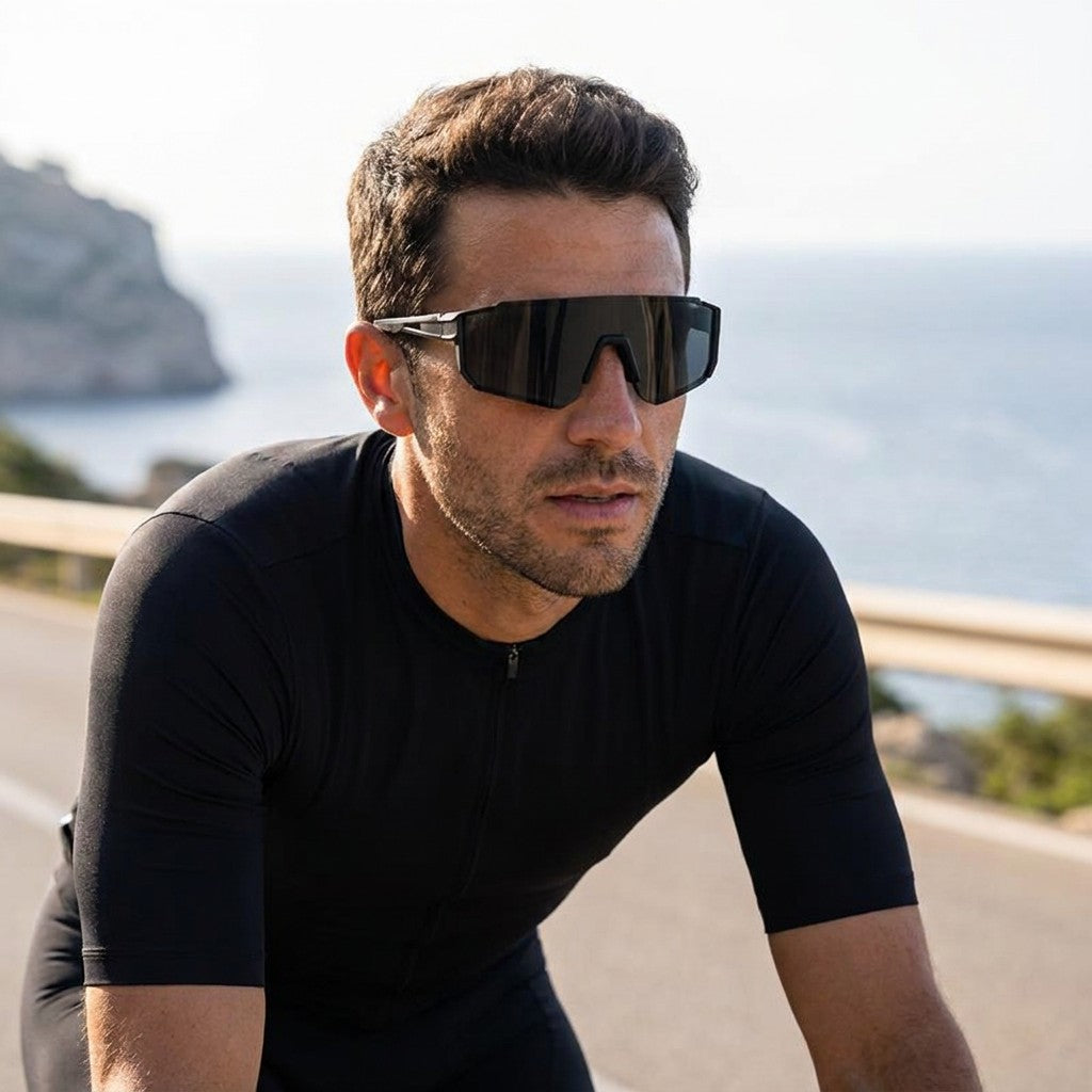 Marciana Sport Sunglasses — Black / Smoke, worn by a man road cycling on a sunny Mallorca coast road