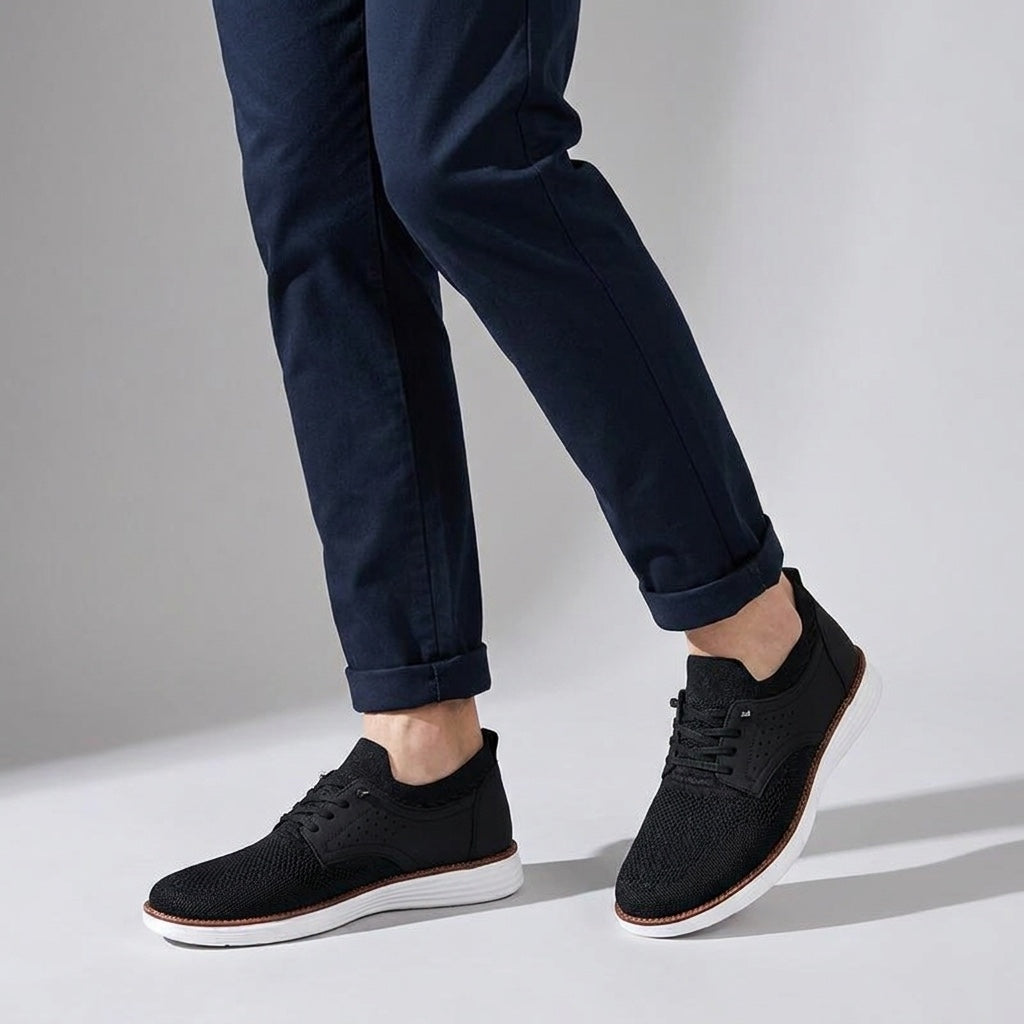 Formia Mesh Sneakers — Black, knee-down, studio backdrop, male model dark navy chinos