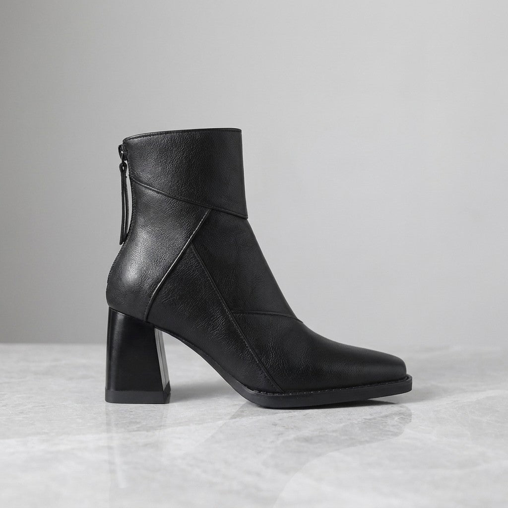 Arona Paneled Ankle Boots — Black, single boot in side profile on light grey marble