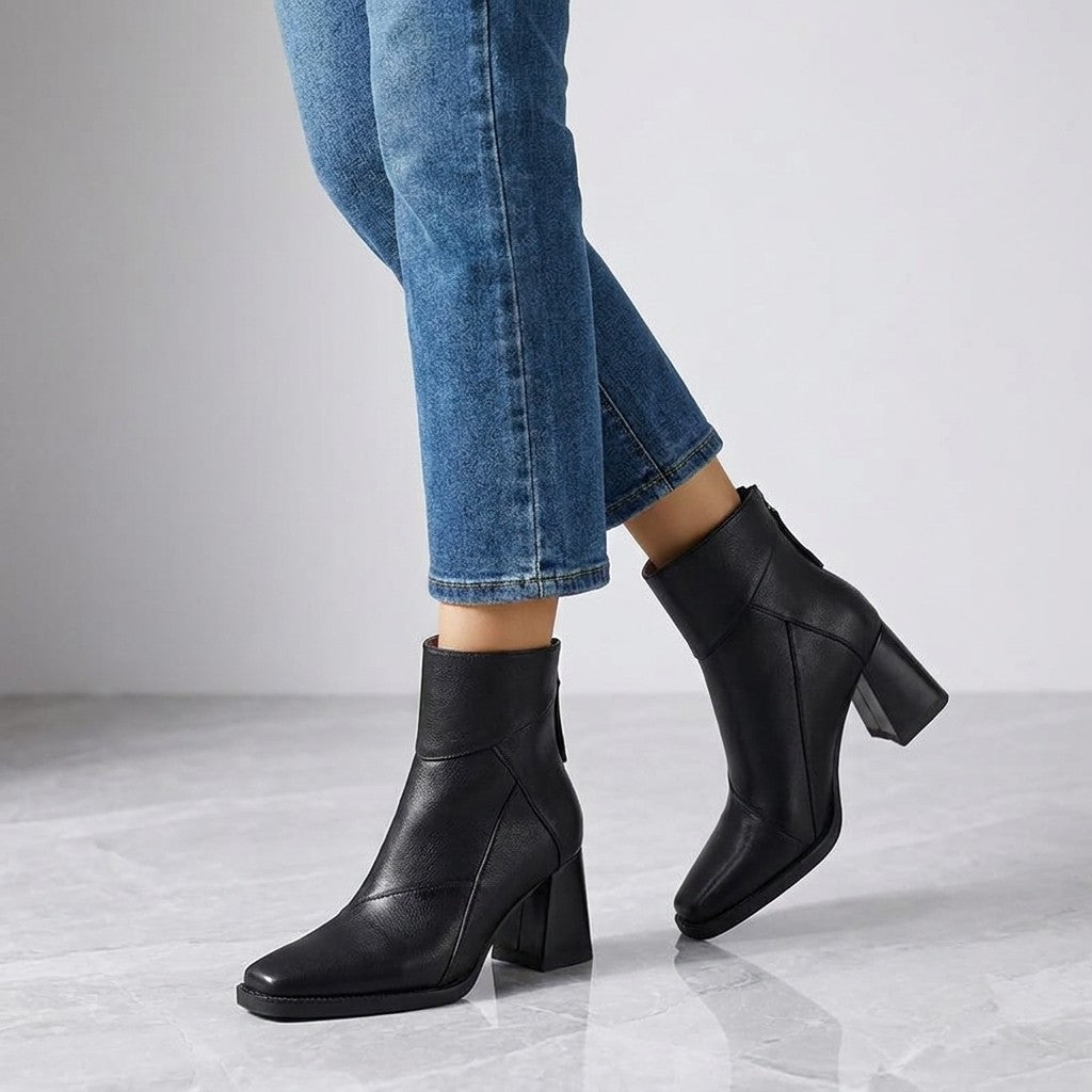 Arona Paneled Ankle Boots — Black, worn with cropped blue jeans, knee-down on light grey marble