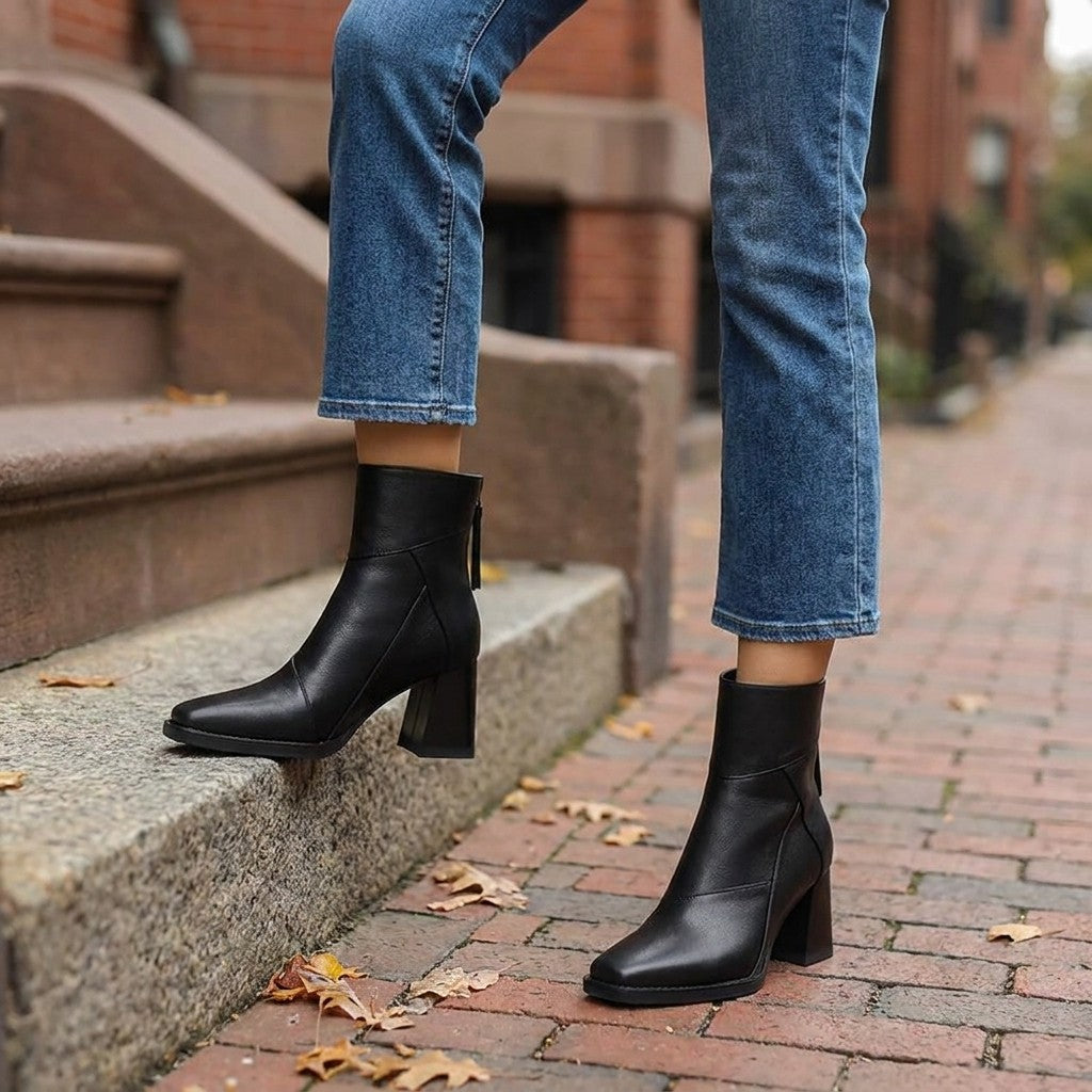 Arona Paneled Ankle Boots — Black, worn with cropped blue jeans on a brick sidewalk by brownstone steps