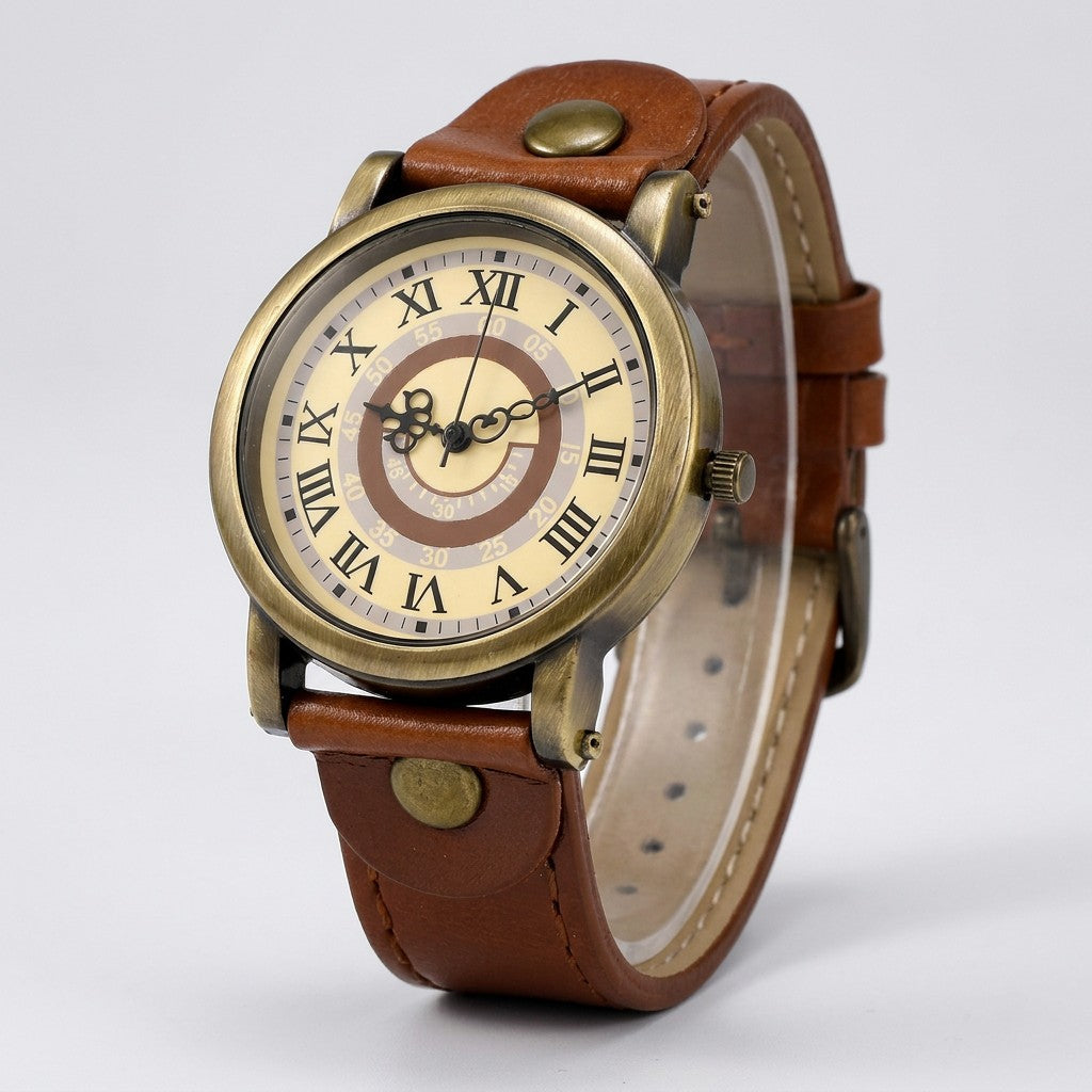 Tarquinia Bronze-Tone Watch — Bronze / Tan, cream Roman-numeral dial on a light-grey studio backdrop