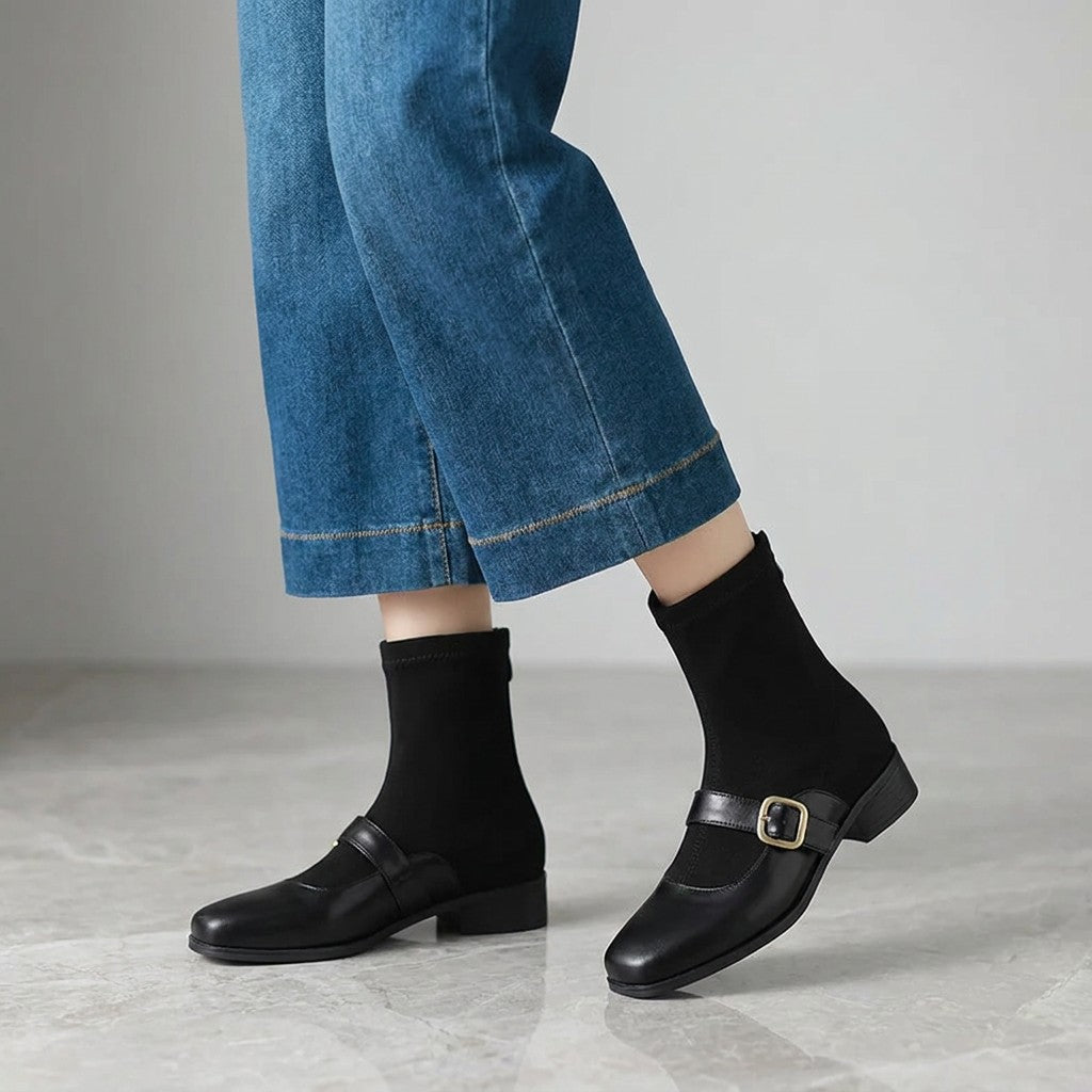 Sondrio Buckled Ankle Boots — Black, worn by a woman, knee down, on grey marble